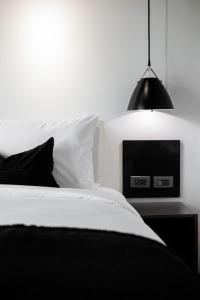 BedTime Hotel Samui في شاطئ تشاوينغ: غرفة نوم سوداء وبيضاء مع سرير ومصباح