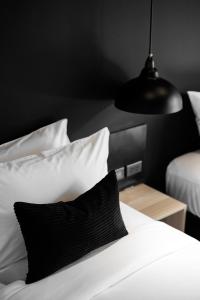 BedTime Hotel Samui في شاطئ تشاوينغ: سرير مع وسائد سوداء وبيضاء ومصباح أسود