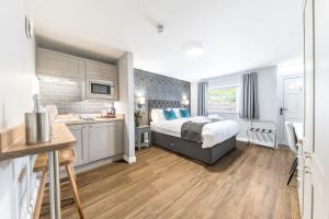 a bedroom with a large bed and a kitchen at Chequers Lodge- Dalton-in- Furness- Self check in- for professionals and tourists in Dalton in Furness