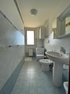 La salle de bains blanche est pourvue d'un lavabo et de toilettes. dans l'établissement Leto Apartment, à Letojanni
