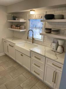 uma cozinha com armários brancos, um lavatório e uma janela em The Warm & Inviting Place em Sioux Falls
