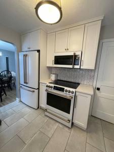 uma cozinha com armários brancos, um fogão e um frigorífico em The Warm & Inviting Place em Sioux Falls