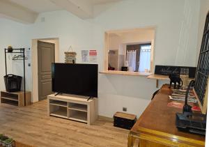 sala de estar con TV de pantalla plana en un soporte en Le Limouxin jungle Wifi, petit balcon *Oc Keys, en Limoux