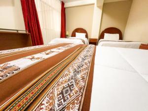 a room with three beds with white sheets and a rug at La Mansion Casa Hotel in Andahuaylas