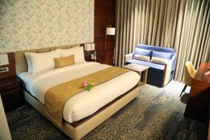 a bedroom with a large bed and a blue chair at peninsula the boutique hotel in Panchkula