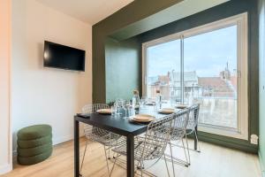 ein Esszimmer mit einem Tisch, Stühlen und einem Fenster in der Unterkunft 3 bedroom apartment on the Grand Place in Lille