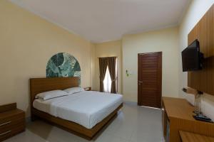 a bedroom with a bed and a flat screen tv at Cove Raddeyapa in Canggu