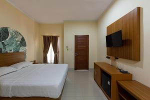 a bedroom with a bed and a flat screen tv at Cove Raddeyapa in Canggu