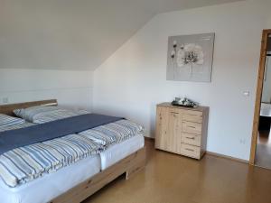 a bedroom with a bed and a wooden dresser at Rudis Ferienwohnung in Kirchham