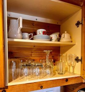 a cupboard filled with glasses and plates and bowls at 'Little Grebe' - Secluded Rustic Lodge - Fishermans delight. in York