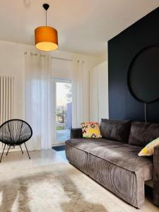 sala de estar con sofá marrón y ventana en La Baraque Calais Blériot 2, en Sangatte