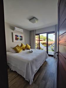 a bedroom with a white bed with yellow pillows at Pousada Waikiki Boutique in Pipa +81 photos