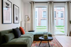 un soggiorno con divano verde e ampia finestra di Apartment in a new residence with parking a Mouvaux