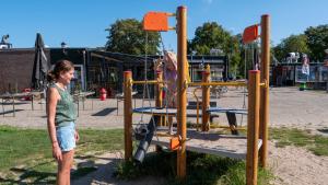uma mulher em pé em frente a um parque infantil em Camping de Krabbeplaat em Brielle