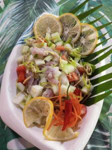 a plate of food with vegetables and lemon slices at Balai Ko Beach & Cottages in El Nido