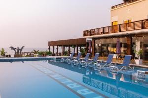 a swimming pool with chairs and a building at Marlin Resort in Kasoa