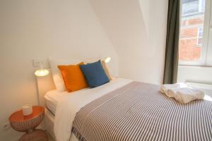 a bedroom with a bed with colorful pillows and a window at Lille Grand Place - Hypercentre ! in Lille