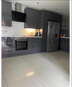 a kitchen with gray cabinets and a stainless steel refrigerator at Macs Belfast Single bedroom in Belfast