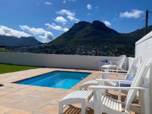 um pátio com cadeiras e uma piscina com uma montanha em Cockleshells Beach Cottage na Cidade do Cabo