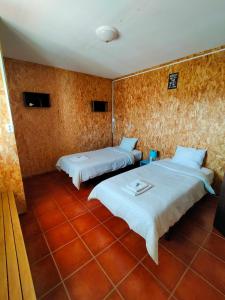 two beds in a room with red tiles at I Ka Hale in Vila Nova de Milfontes