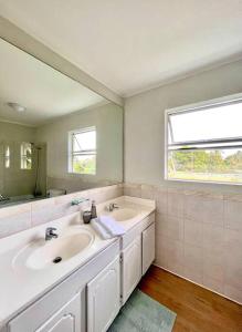 Baño blanco con 2 lavabos y espejo en Freight’s Reach #6 Cotton Bay en Christ Church