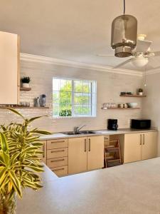 a kitchen with white cabinets and a sink and a window at Freight’s Reach #6 Cotton Bay in Christ Church