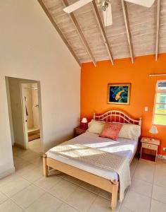 a bedroom with a bed with an orange wall at Freight’s Reach #6 Cotton Bay in Christ Church