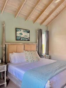 a bedroom with a bed with blue sheets and a window at Freight’s Reach #6 Cotton Bay in Christ Church