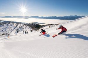 2 personnes font du ski sur une piste enneigée dans l'établissement Appartement mit Seeblick am Ossiacher See, à Villach