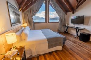 a bedroom with a large bed with a large window at El Faro Boutique Hotel & Spa by DON in Villa La Angostura