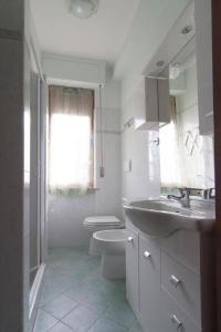 ein weißes Bad mit einem Waschbecken und einem WC in der Unterkunft Appartamento PE in Follonica