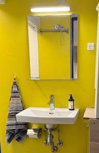 a yellow bathroom with a sink and a mirror at Millinge Gamle Skole in Millinge