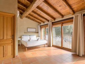 a bedroom with a bed and a large window at Aiguabella - Allotjaments Rurals in Sant Feliu de Pallerols