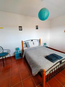 a bedroom with a bed and a blue lamp at I Ka Hale in Vila Nova de Milfontes