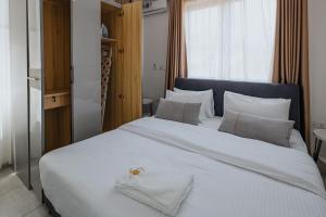 - une chambre avec un grand lit blanc et des oreillers blancs dans l'établissement The Avery Apartments at Odomaa Place, East Airport, à Accra