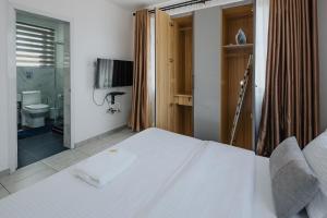 a bedroom with a white bed and a bathroom at The Avery Apartments at Odomaa Place, East Airport in Accra