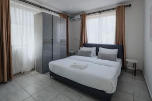 een slaapkamer met een groot wit bed en een douche bij The Avery Apartments at Odomaa Place, East Airport in Accra