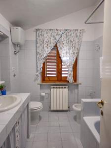łazienka z umywalką, toaletą i oknem w obiekcie Casa Olea w mieście Montarice