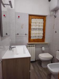 een badkamer met een wastafel, een toilet en een raam bij Casa Olea in Montarice