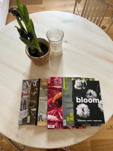 un tavolo bianco con un libro e una pianta sopra di Bloom as you are a Bologna
