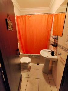 a bathroom with an orange shower curtain and a sink at I Ka Hale in Vila Nova de Milfontes