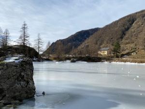 a river with snow on the ice and a house at Chambre d'Hôtes Casa Mia in Belvédère