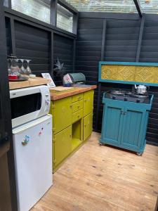 cocina con armarios amarillos y azules y fogones en Boho Glamping en Wilderness