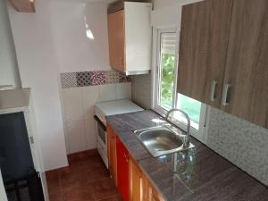 una pequeña cocina con fregadero y ventana en Seminario Cottage, en Tortosa