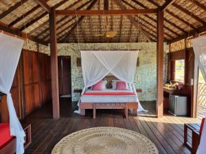 a bedroom with a bed with a mosquito net at Vila Guará in Atins