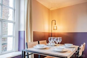 a dining room table with chairs and wine glasses at Guest Homes - Chandan Court Apartment in Bewdley