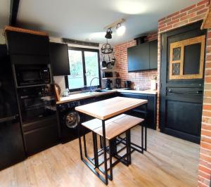 uma cozinha com armários pretos e uma mesa de madeira em La Buissonnière em Veulettes-sur-Mer