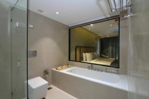 a bathroom with a tub and a toilet and a mirror at ORIGIN BOUTIQUE HOTEL in Goa +67 photos