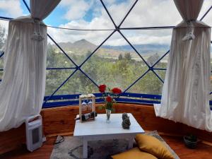 a room with a large window with a table and flowers at Glamping blue. in Guatavita