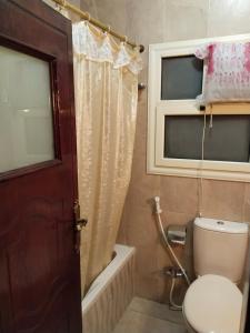 a bathroom with a toilet and a tub and a window at شقة راقية مطلة علي كورنيش النيل المعادي - عوائل فقط in Cairo